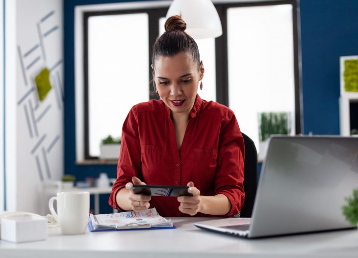 empresaria sentada na mesa olhando celular